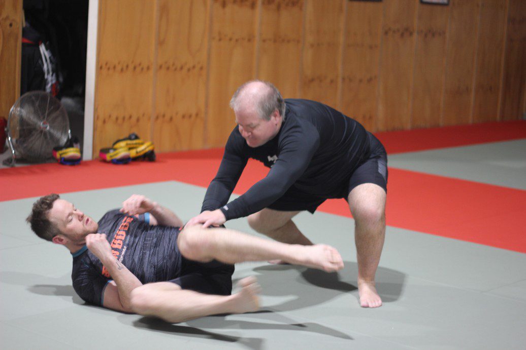 Two students at Eltham Martial Arts Academy practicing ground defense techniques during a self-defence class, showcasing practical grappling training.